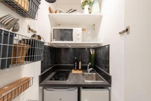 eine Küche mit einer Spüle und einer Mikrowelle in der Unterkunft Geranimus Versailles Charost in Versailles