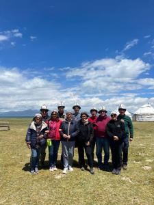 a group of people posing for a picture in a field at Ulush Yurts in Naryn