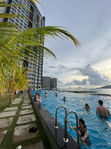 people in a swimming pool next to a tall building at CASA ABODE - Jesselton Quay (Sea View) in Kota Kinabalu