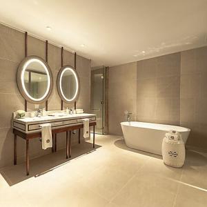 a bathroom with a tub and a sink and mirror at Angsana Oceanview Residences by Laguna Phuket in Bang Tao Beach