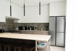 a kitchen with white cabinets and a refrigerator at Modern Home 4BR:Pool, Bathtub, Karaoke, Fast WIFI in Tagum