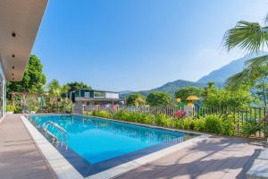 a swimming pool with a fence and mountains in the background at Ami Villa Ba Vì in Ba Vì