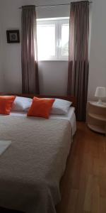 a bedroom with a bed with orange pillows and a window at Apartment in Maslenica 6886 in Maslenica