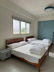 two beds in a room with two windows at 旅居Villa in Dongshan