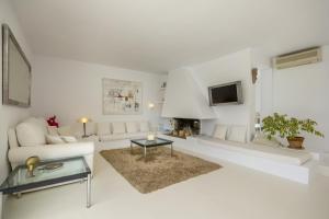 Sala de estar blanca con sofá blanco y chimenea en Casa Flopos - Ibiza, en Nuestra Señora de Jesús