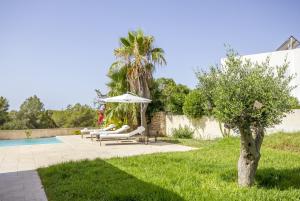 un patio con sombrilla y tumbonas junto a la piscina en Casa Flopos - Ibiza, en Nuestra Señora de Jesús
