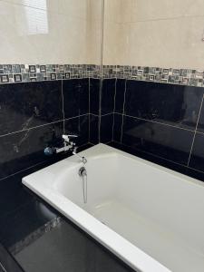 uma banheira branca numa casa de banho com azulejos pretos em 旅居Villa em Dongshan