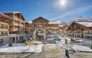 a ski lodge with snow covered mountains in the background at Résidence Prestige Odalys Le Mont d'Auron in Auron