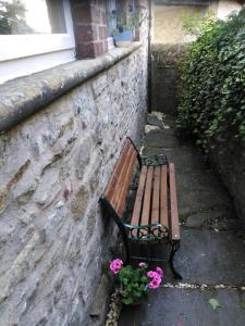 a bench sitting next to a stone wall with flowers at Upside down in Settle. Stylish, central and cosy in Settle