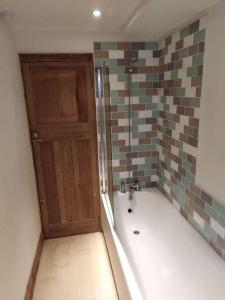 a bathroom with a bath tub and a wooden door at Upside down in Settle. Stylish, central and cosy in Settle
