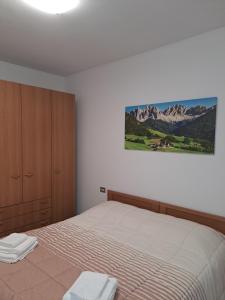 1 dormitorio con 1 cama y una pintura en la pared en VALTELLINA SONDRIO HOLIDAYS en Sondrio