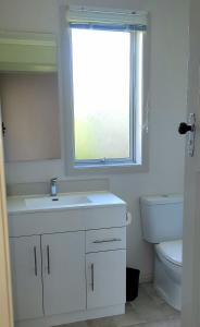 La salle de bains est pourvue d'un lavabo, de toilettes et d'une fenêtre. dans l'établissement The Old Parsonage, à Reefton
