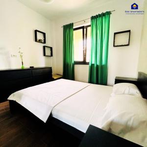 - une chambre avec un grand lit et des rideaux verts dans l'établissement GooApartments Three, à Mamaia Nord – Năvodari