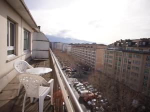 einen Balkon mit 2 Stühlen und einem Tisch auf einem Gebäude in der Unterkunft Primadom Aparthotel in Genf