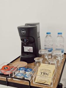 een tafel met een koffiezetapparaat en enkele kopjes en flessen water bij Charming Senglea Studio in Senglea