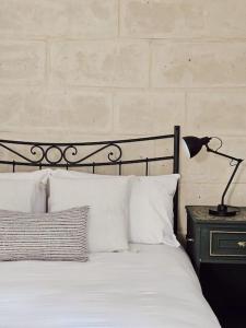 een bed met witte kussens en een lamp op een tafel bij Charming Senglea Studio in Senglea