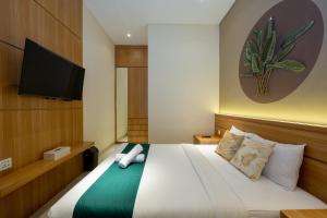 1 dormitorio con 1 cama y TV de pantalla plana en Cove Tripuri House Bali, en Denpasar