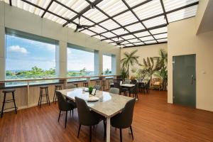 a dining room with tables and chairs and large windows at Cove Tripuri House Bali in Denpasar