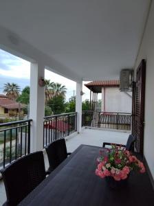 una mesa con sillas y un jarrón de flores en el balcón en Vrasna Luxury Apartment en Nea Vrasna
