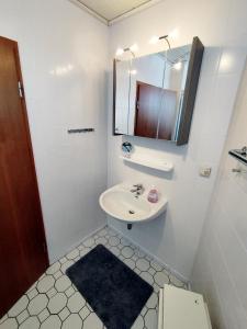 ein weißes Badezimmer mit einem Waschbecken und einem Spiegel in der Unterkunft Steinwarder 9 - Haus "Seeschwalbe" ST9 028 Steinwarder 9 in Heiligenhafen