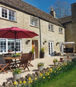 a table with an umbrella in front of a building at Thames Head Wharf - Historic Cotswold Cottage with Stunning Countryside Views in Cirencester