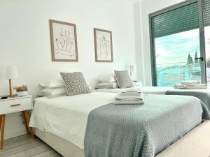 2 camas num quarto branco com uma janela em Vila Meluna em Albufeira