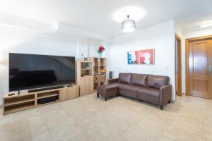 a living room with a couch and a large flat screen tv at Bungalow PLAYA POBLA DE FARNALS in Las Canteras