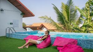 a woman sitting on pink pillows next to a swimming pool at Mad Monkey Luang Prabang in Luang Prabang
