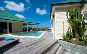 une maison avec une terrasse en bois à côté d'une piscine dans l'établissement Luxury Vacation Villa 17, à Le Marigot