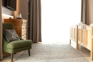 a living room with a green chair and a crib at Hotel Margherita in Livigno