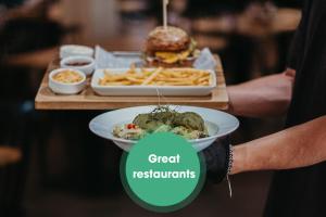 una persona sosteniendo un plato de comida con una hamburguesa y papas fritas en Demänová Rezort, en Liptovský Mikuláš