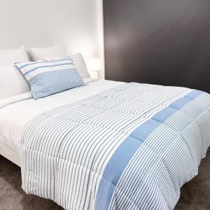 a bed with a blue and white striped blanket at Urban Locale: Bars, eats & shops in Christchurch