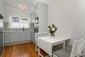 una cucina con armadi bianchi, tavolo e sedie di Coastal Living Just Metres From Coogee Beach a Sydney