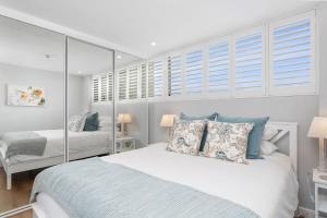 a bedroom with a large bed with blue pillows at Modern Manly Apartment with Stunning Views, Pool in Sydney