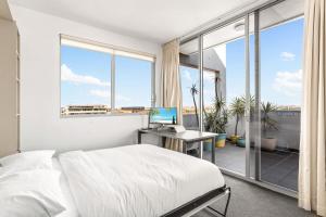 Spacious 2-Bed with Two Balconies with City Views في سيدني: غرفة نوم مع سرير ومكتب مع جهاز كمبيوتر