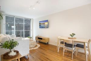 a living room with a table and a dining room at Chic Beachside Apartment Freshwater in Freshwater