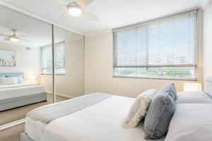 a white bedroom with a bed and a window at Chic Beachside Apartment Freshwater in Freshwater
