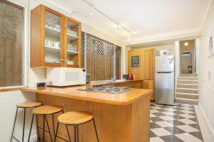 uma cozinha com um balcão com bancos e um frigorífico em Comfortable Terrace in Central Location em Sydney