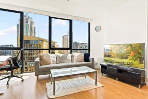 a living room with a couch and a flat screen tv at Modern 1-Bed in CBD with Views near Chinatown in Sydney