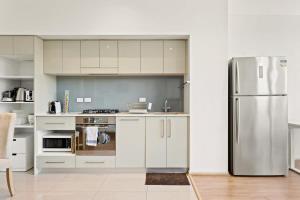 a kitchen with white cabinets and a stainless steel refrigerator at Modern 1-Bed in CBD with Views near Chinatown in Sydney