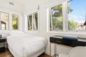 Biała sypialnia z oknami, łóżkiem i biurkiem w obiekcie Modern 2-Bed Unit in the Heart of Bondi w mieście Sydney
