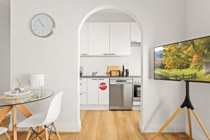 biała kuchnia ze stołem i telewizorem w obiekcie Modern 2-Bed Unit in the Heart of Bondi w mieście Sydney
