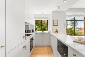 a kitchen with white cabinets and a large window at Boutique 2-Bed with Stunning Sydney Harbour Views in Sydney