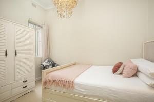 um quarto branco com uma cama e um lustre em Comfortable Terrace in Central Location em Sydney