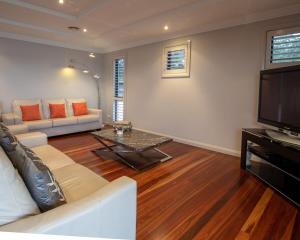 a living room with a couch and a tv at Premium Views from Spacious Beachside Home in Batemans Bay