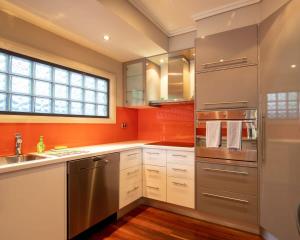 a kitchen with orange walls and stainless steel appliances at Premium Views from Spacious Beachside Home in Batemans Bay