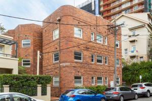 a brick building with cars parked in front of it at Art Deco Apartment Meters Away From The Beach in Sydney