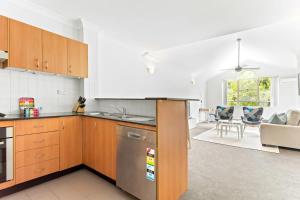 a kitchen with wooden cabinets and a living room at Pristine 2-Bed Near Marrickville Village in Sydney