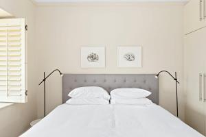 Dormitorio blanco con cama con sábanas y almohadas blancas en Clovelly Beach House - Sea, Sand and Exclusivity en Sídney