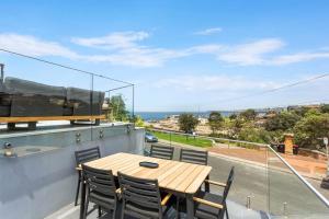 drewniany stół na balkonie z widokiem na ocean w obiekcie Clovelly Beach House - Sea, Sand and Exclusivity w mieście Sydney
